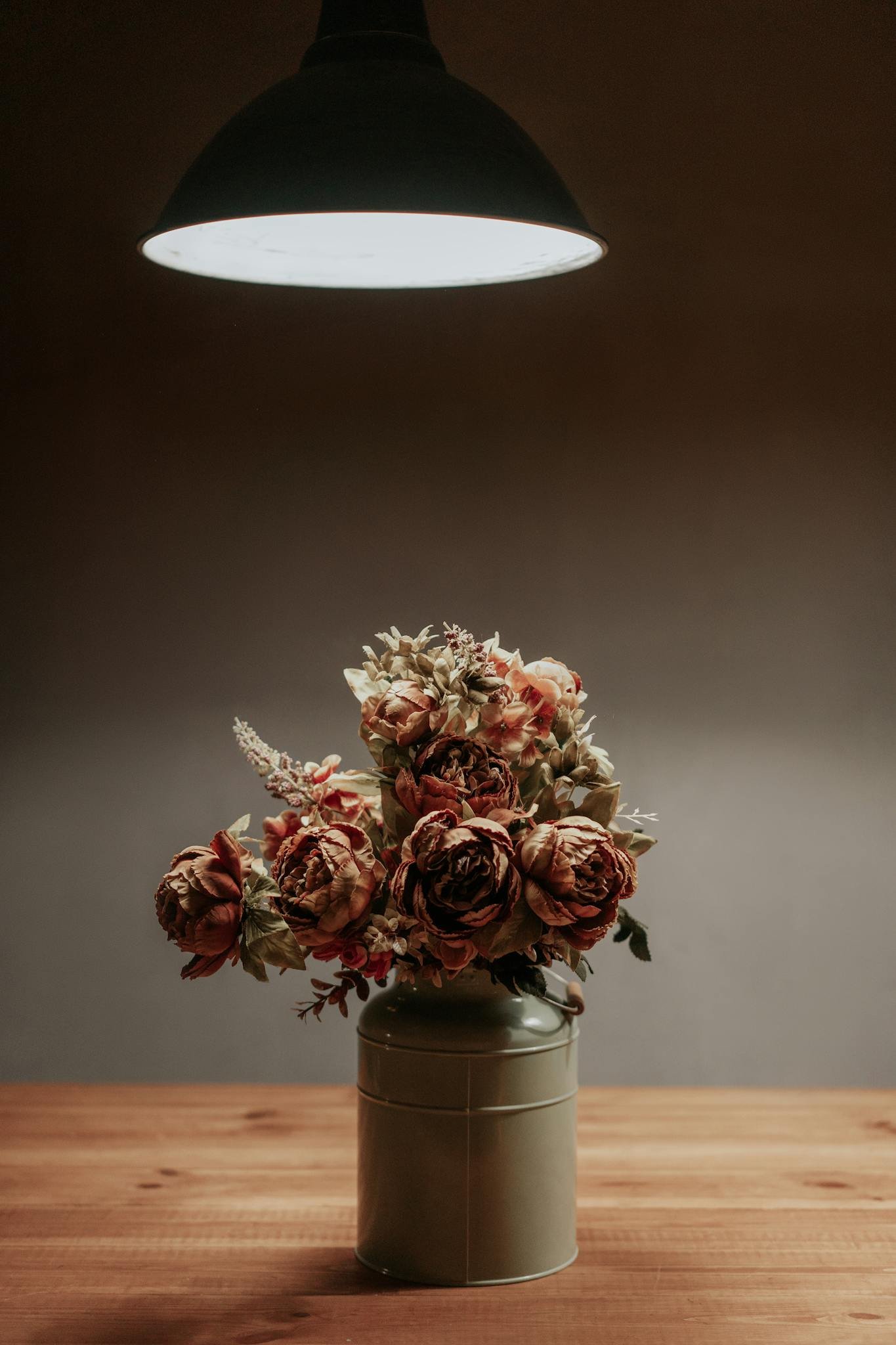A bouquet of flowers in a vase under soft lighting, creating a warm, cozy atmosphere.